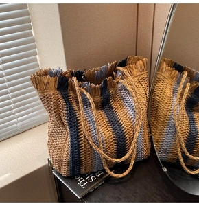 Detail of colorful woven straw tote with blue and brown stripes and fringe trim