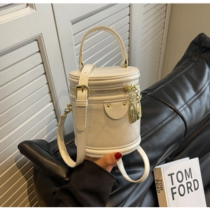 Detail of cream bucket bag with quilted leather texture and gold lock-shaped charm