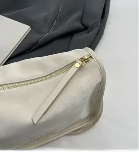 Détail de la fermeture éclair dorée et de la texture en similicuir crème du sac