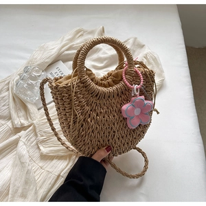 Detailed close-up of woven straw bag with floral charm and drawstring fabric lining