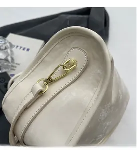 Gros plan d'un sac crème texturé montrant les détails dorés et le motif à vagues d'eau