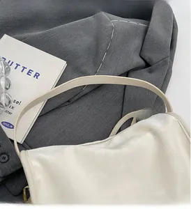Détail de la bandoulière d'un sac crème confortable avec une texture de tissu doux et chic