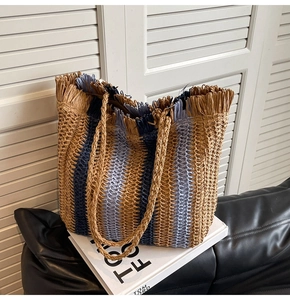 Detail of hand-woven straw tote with vertical blue stripes and fringe edge texture