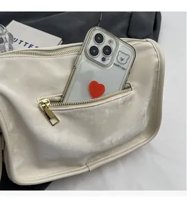Détail d'un sac bandoulière beige avec poche zippée avant pour le rangement d'un smartphone