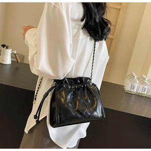 Close-up of quilted black chain bucket bag with drawstring and triangle hardware