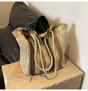 Close-up of the woven straw tote with striped pattern and fringe edge detail
