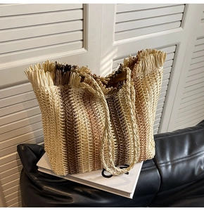 Close-up of three-tone striped straw tote bag featuring tassel fringe and rope handles