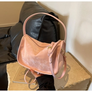 Détail du sac Boston en cuir rose clair avec texte embossé et finitions en métal doré