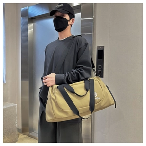 Man carrying large khaki travel duffle bag with black adjustable shoulder strap