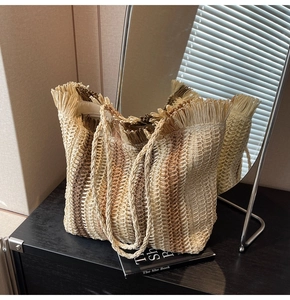 Detail of hand-woven straw tote with vertical stripes and long fringe trim design