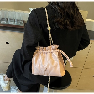 Detail of quilted bucket bag featuring a chain strap and metal bead adjustment