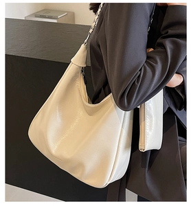 Close-up of cream faux leather tote bag with metal chain strap and inner pouch