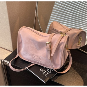 Gros plan du sac Boston en daim rose avec lettres XICH XICH et finitions dorées