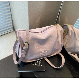 Détails macro du sac Boston en daim rose poudré avec logo embossé et finitions dorées