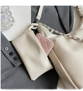 Detail of cream tote with chain strap, outer pouch, and pink quilted wallet on a blazer
