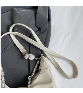Detail of adjustable cream leather strap and silver chain on a stylish tote bag