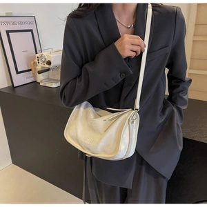 Détail du sac demi-lune en cuir blanc avec texte XICH XICH embossé et bandoulière réglable