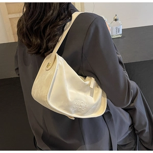 Détail du sac hobo blanc crème en cuir avec lettrage embossé et boucle dorée élégante