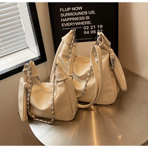 Detail of cream white tote bag set with pleated texture and stylish metal chain strap