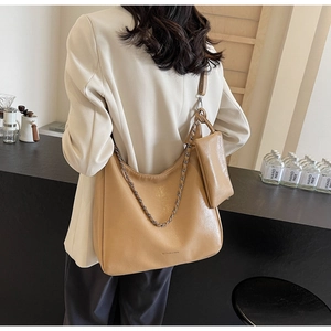 Detail of light tan tote bag showing chain strap and matching small zipper pouch