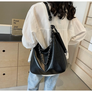 Detail of black tote bag with silver chain strap and smooth leather texture for daily commute