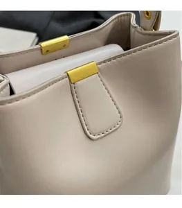 Détail du sac seau en cuir beige montrant les coutures fines et la boucle dorée