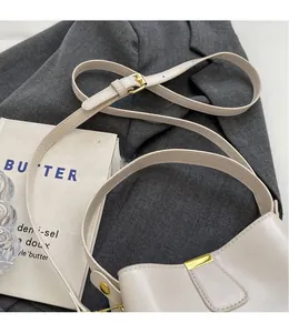 Détail de la bandoulière réglable avec boucle en métal doré sur le sac seau beige