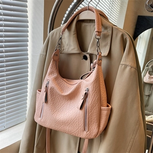 Sac fourre-tout en cuir texturé rose avec zips argentés sur un trench-coat beige