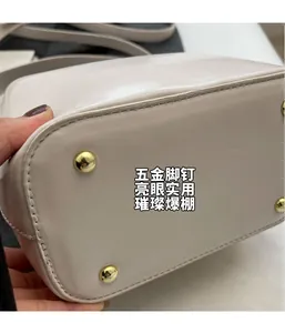 Détail des pieds en métal doré et des coutures sur le sac seau blanc cassé chic