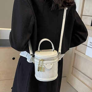 Beige quilted leather bucket bag with gold hardware and shoulder strap shown on model