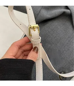 Détail de la bandoulière en cuir blanc avec boucle de réglage carrée en métal doré