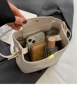 Vue intérieure du sac seau crème montrant l'espace pour téléphone, portefeuille et parfum