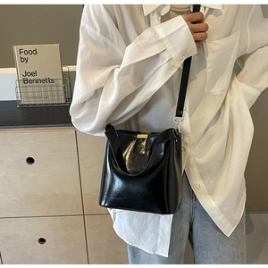 Détail d'un sac seau noir avec garniture dorée et double bandoulière sur mannequin