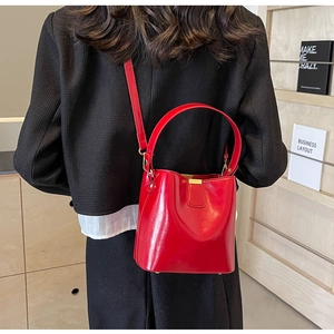 Gros plan d'un sac seau en cuir rouge brillant avec des détails dorés chic