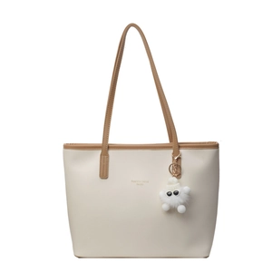 Large cream tote bag with brown straps and plush charm, ideal for stylish daily commuting