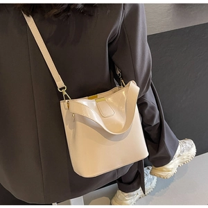 Détail d'un sac seau crème minimaliste avec boucles dorées et bandoulière réglable