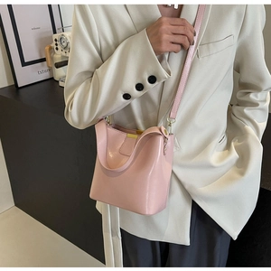 Détail d'un sac seau en cuir rose clair avec bandoulière réglable et éléments métalliques