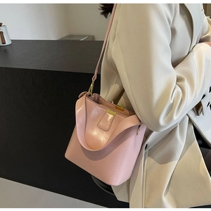 Gros plan d'un sac seau rose clair avec ferrures dorées porté par un mannequin