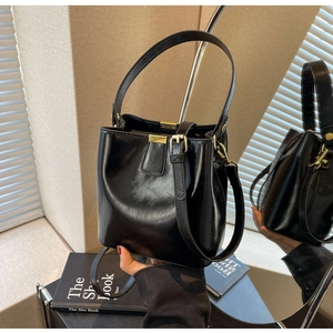Détail d'un sac seau noir avec fermoir doré montré sous plusieurs angles grâce au miroir