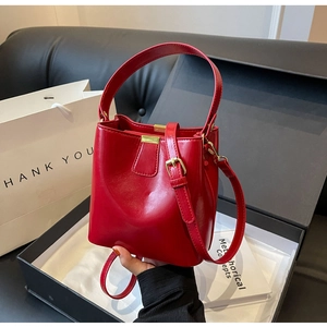 Vue détaillée d'un sac seau rouge vernis avec finitions dorées et poignée élégante