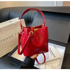 Vue détaillée du sac seau en cuir verni rouge avec boucle dorée et bandoulière réglable