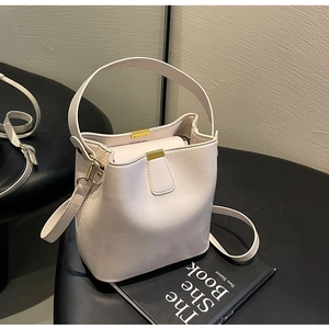 Détail d'un sac seau en cuir beige avec garniture dorée sur un tabouret
