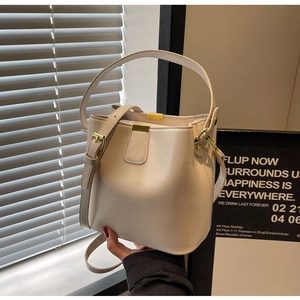 Détail du sac seau crème montrant la bandoulière réglable et la boucle dorée en métal