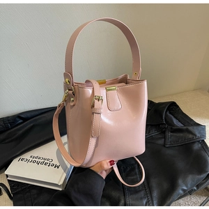 Vue détaillée du sac seau rose en cuir avec ferrures dorées sur du cuir noir