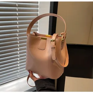 Gros plan d'un sac seau en cuir rose avec boucles dorées et bandoulière réglable
