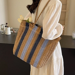 Large striped straw tote bag for beach vacations shown with a white outfit and flowers