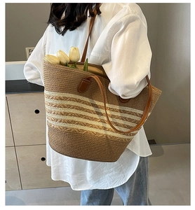 Détail du sac cabas en paille rayée avec anses en cuir et fleurs décoratives