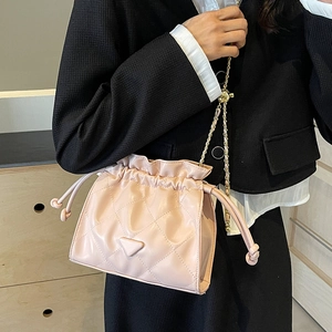 Pale pink quilted chain bucket bag with drawstring closure and metal logo plaque