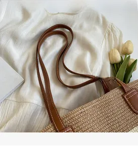 Détail du sac cabas en paille avec anses en cuir marron et coutures contrastées élégantes