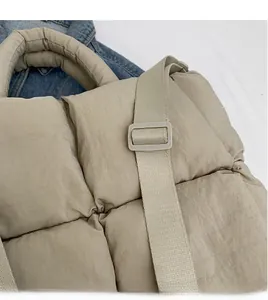 Detail view of beige quilted tote bag with smooth adjustable wide shoulder strap and handle